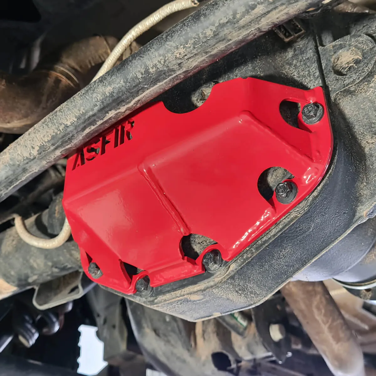Red ASFIR differential skid plate installed on an axle